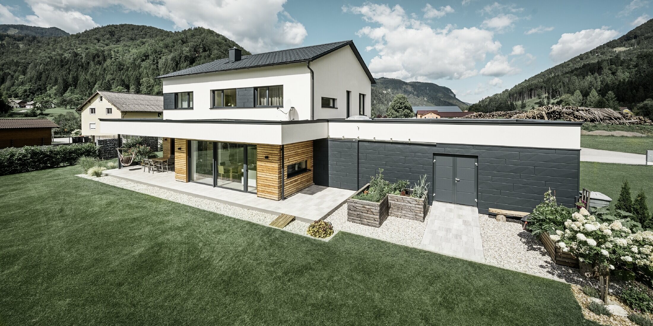Maison individuelle moderne dans un environnement rural, avec les produits de toiture et de façade PREFA. 