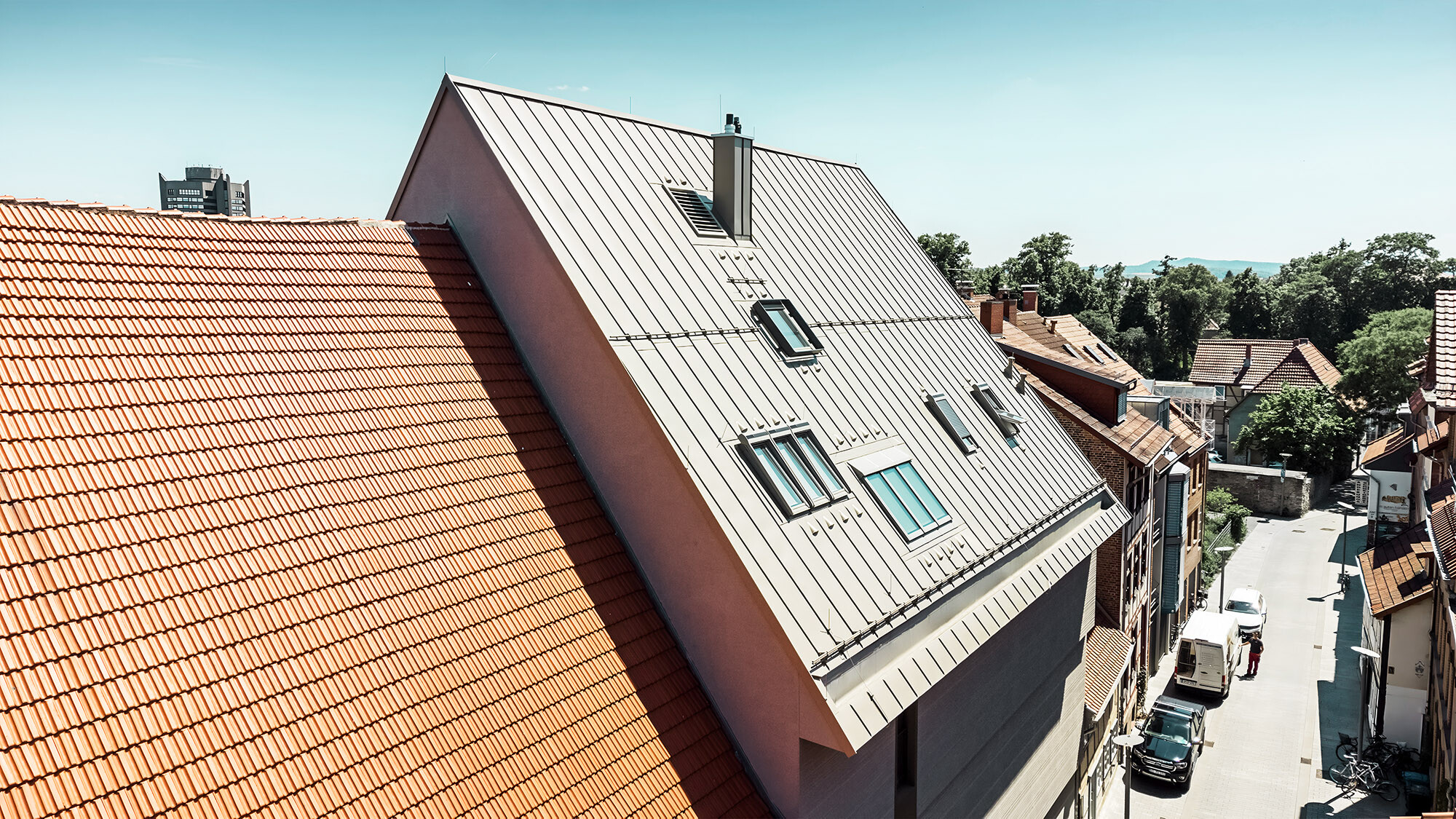 Eine Seitenansicht dieses außergewöhnlichen Daches neben rostfarbenen Flachziegelbauten.
