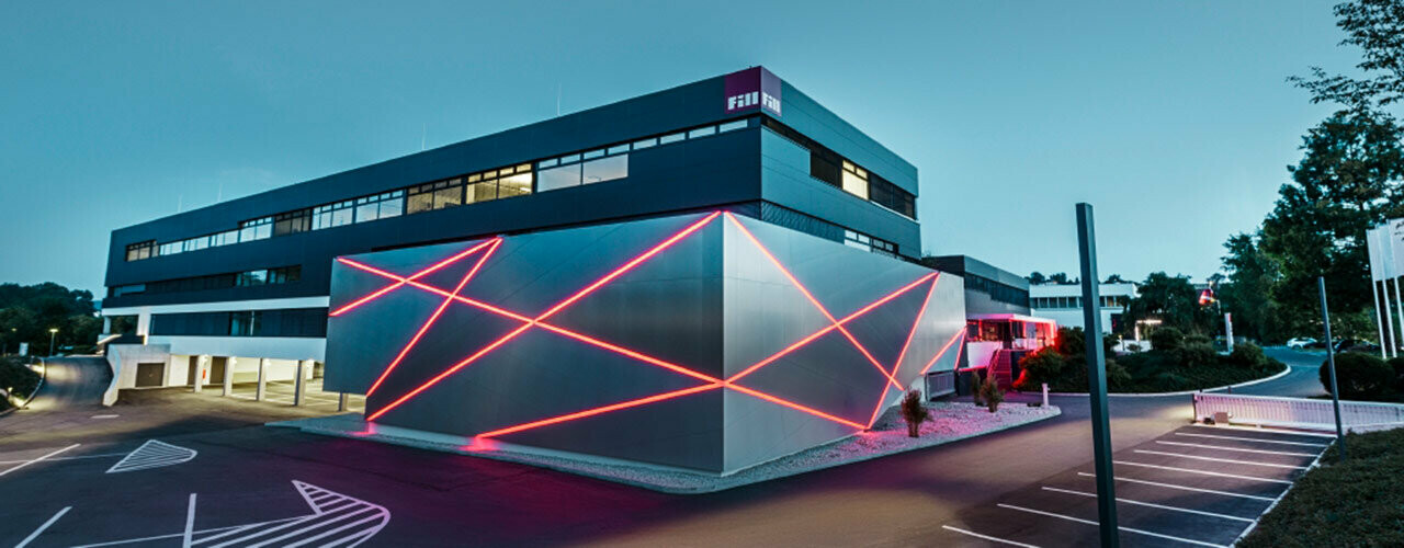 Façade d’un bâtiment de société avec une ligne de bris dans le mur, revêtue de panneaux composites PREFA en aluminium brossé.