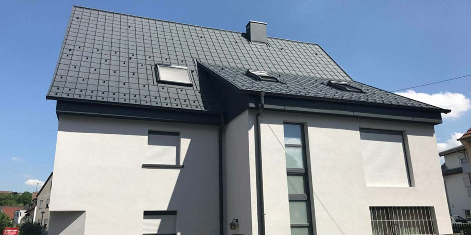 Rénovation d’un toit à deux pans à l’aide de tuiles PREFA, façade blanche