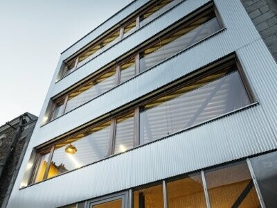L'immeuble de bureaux a été photographié depuis le bas et s'élève dans le ciel. Le bâtiment a été habillé avec le profilé crénelé PREFA dans la couleur aluminium naturel.