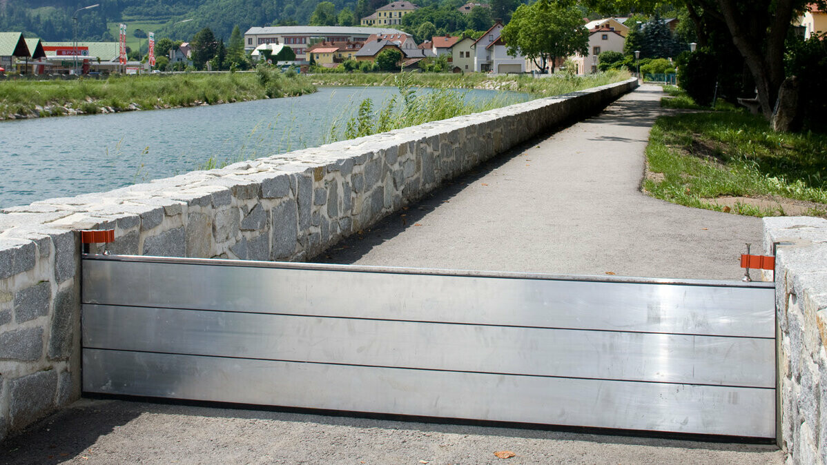 Protection contre les crues PREFA installée à côté d’une rivière  Protection contre les crues PREFA en aluminium