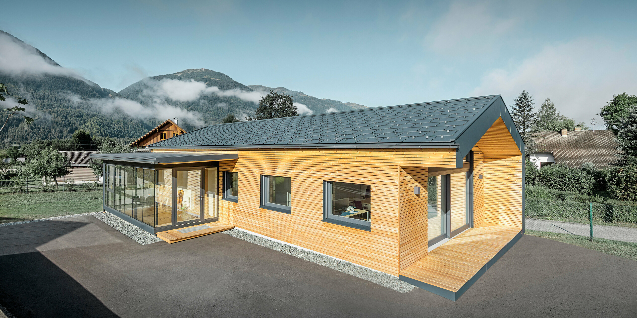 Moderno edificio per uffici con facciata in legno di larice e ampie finestre. I lavori di lattoneria sono stati eseguiti con materiale PREFA in antracite.