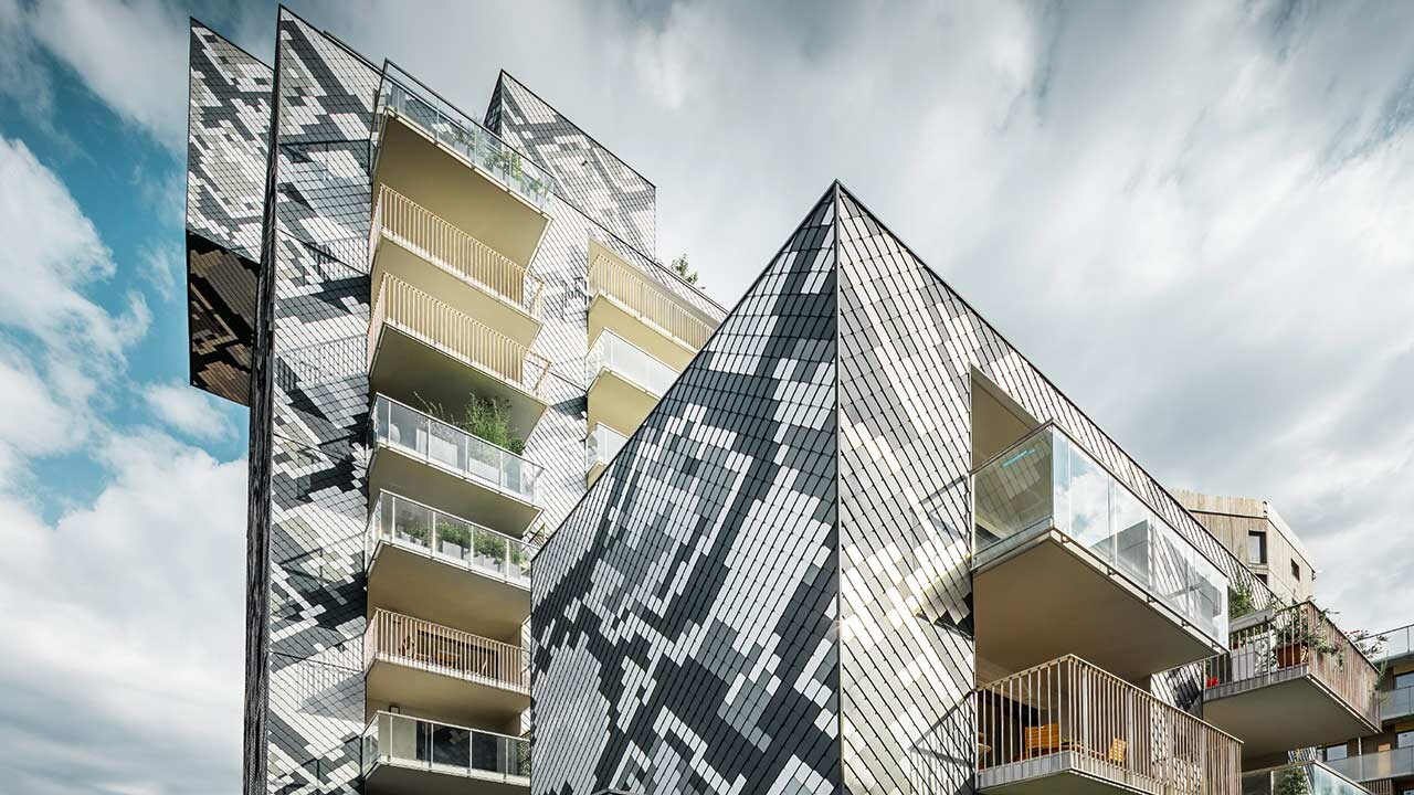 Teilansicht des Wohnhauses Le Python im neuen Stadviertel von Grenoble in Südfrankreich, das Schlangenhaus wurde mit der PREFA Aluminium Wandraute in anthrazit, hellgrau, naturblank und silbermetallic eingedeckt