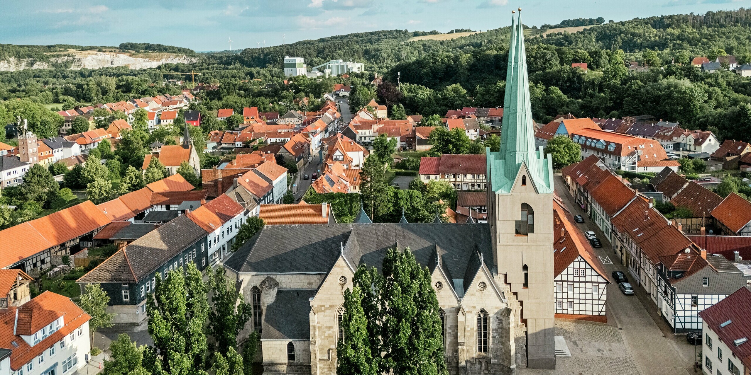 Images aériennes de l'église Saint-Jean d'Ellrich, nichée dans un paysage pittoresque aux toits de tuiles rouges. En son centre : la tour récemment construite, coiffée d'un toit pointu en aluminium PREFALZ vert de gris P.10 – un édifice moderne et chargé d'histoire. La toiture en aluminium de haute qualité impressionne par sa durabilité, sa résistance aux intempéries et son élégance nécessitant peu d'entretien.