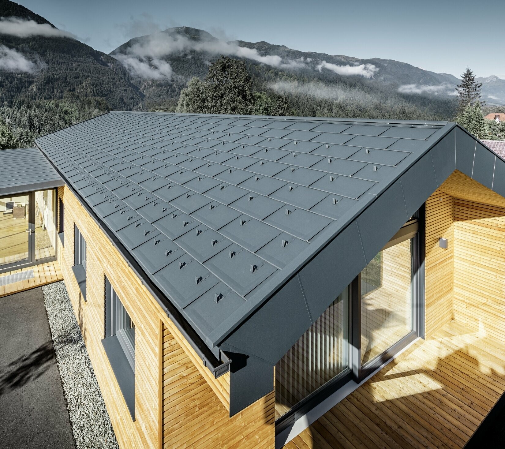 Nouveau bâtiment administratif de Holzbau Faltheiner avec une façade en mélèze, de grandes baies vitrées et une toiture PREFA couleur anthracite.
