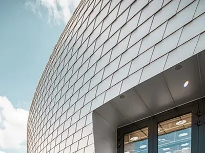 Zoom sur l'entrée de la salle de sport tchèque, qui à été recouverte de 20 000 bardeaux PREFA en aluminium naturel