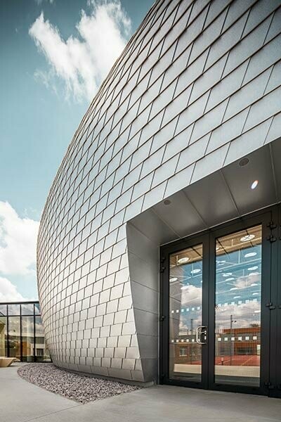 Zoom sur l'entrée de la salle de sport tchèque, qui à été recouverte de 20 000 bardeaux PREFA en aluminium naturel