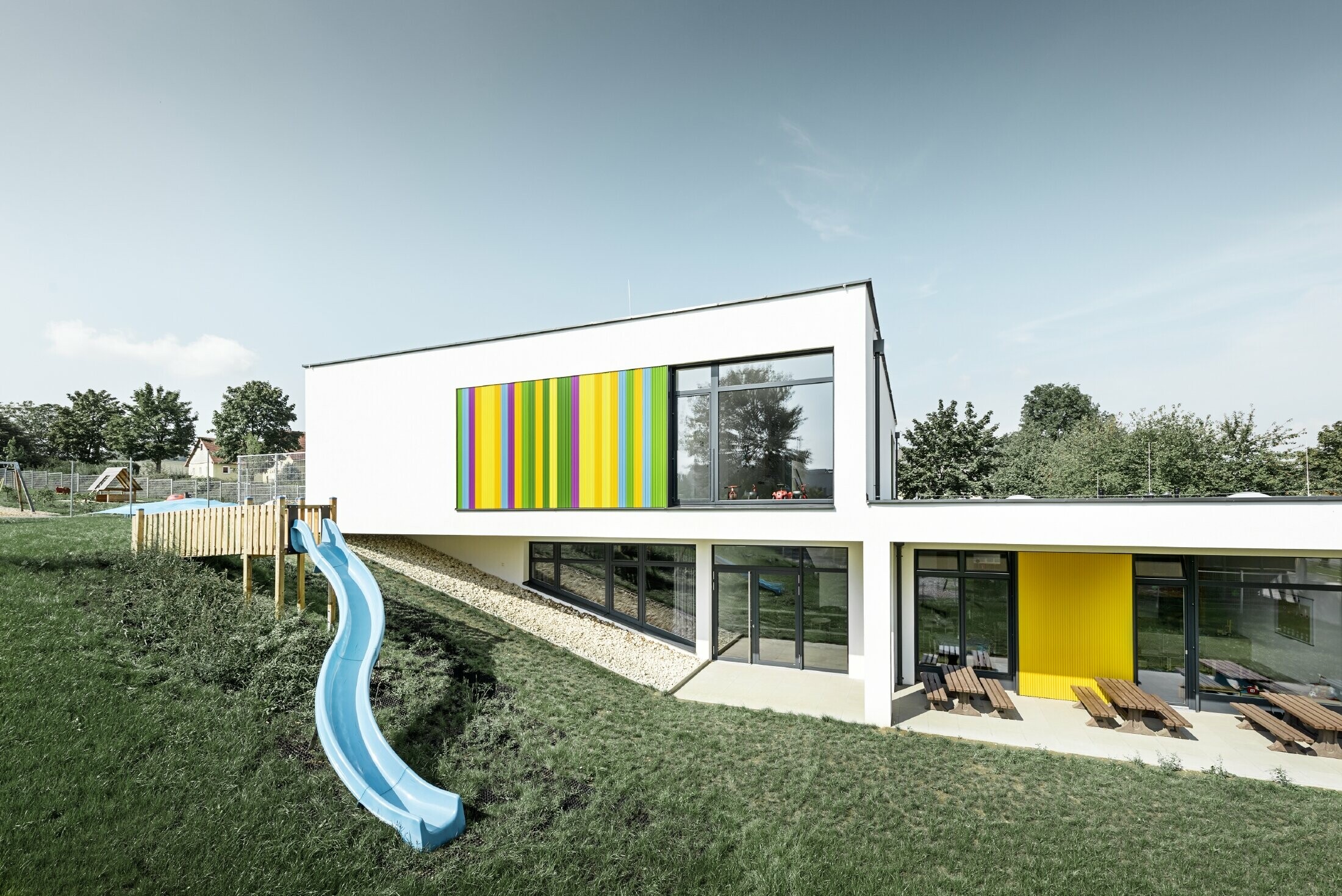 Veduta posteriore della scuola materna ad Hargelsberg con profilo a zeta colorato PREFA in giallo, verde, lilla e blu