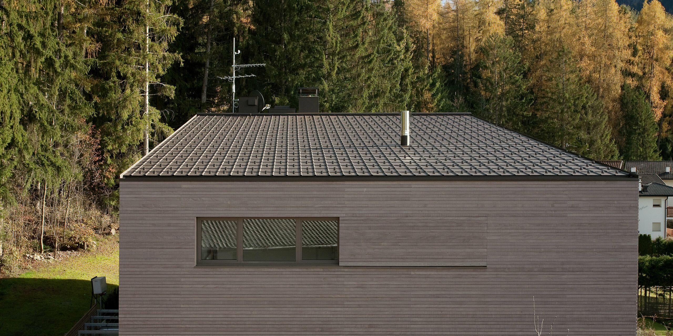 Dachansicht des modernen Gebäudes mit PREFA Dachplatten in P.10 Braun, die sich perfekt in die alpine Landschaft integrieren. Die klare Linienführung des Hauses und das zurückhaltende Design betonen die zeitlose Ästhetik.