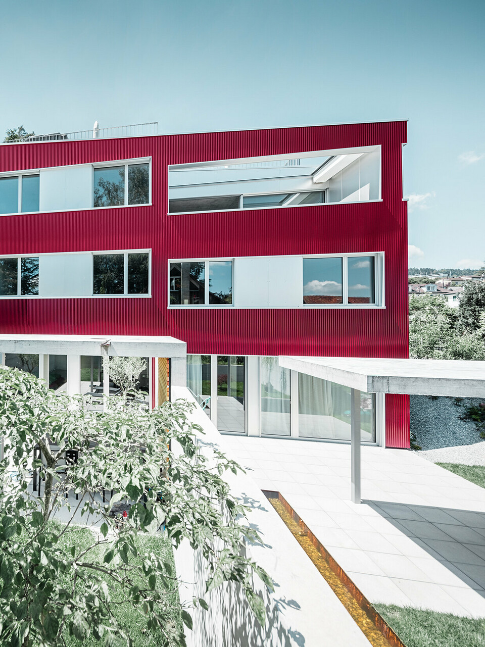 Complesso residenziale con tetto piano e balconi con facciata rosso vino con profilo ondulato PREFA 