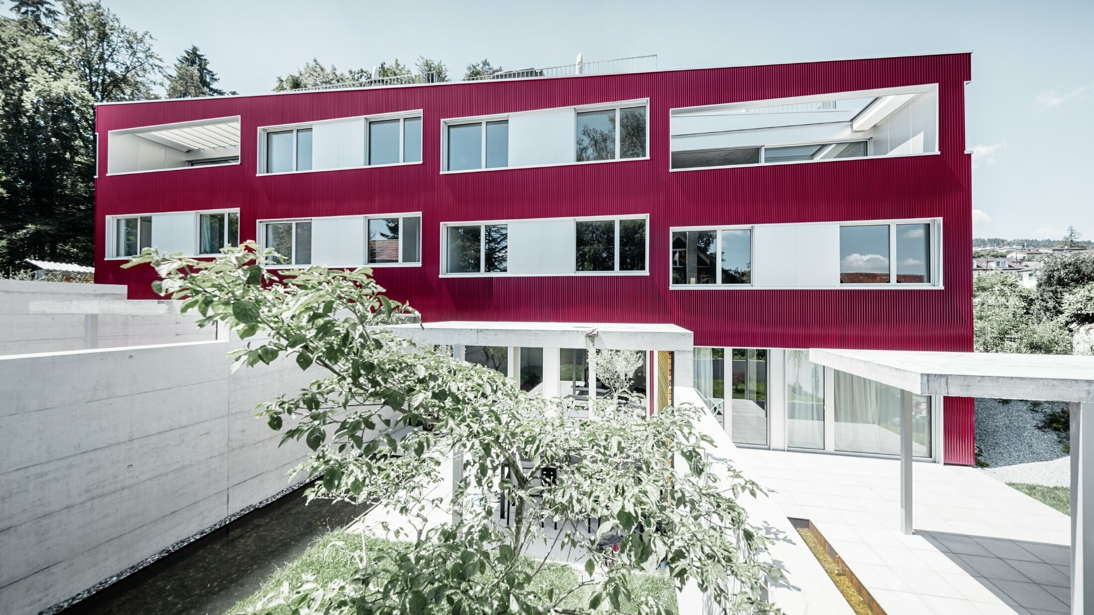 Complexe résidentiel à toit plat et façade de balcons avec profil sinus  bordeaux de PREFA 