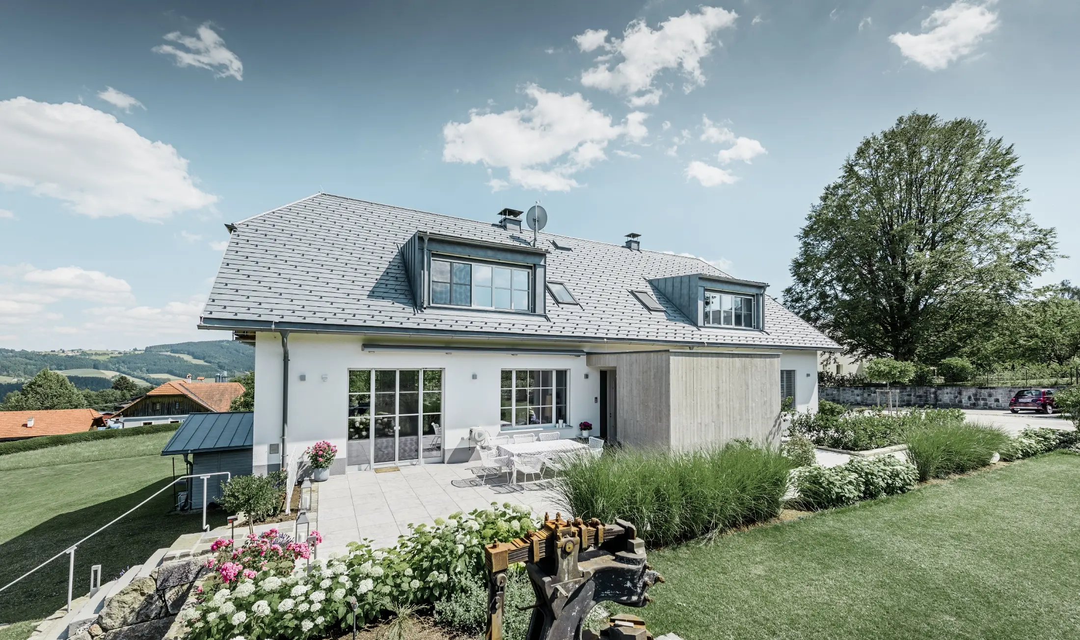 Classica casa unifamiliare con tetto a mezza anca. La casa è stata ristrutturata con scandole PREFA in grigio pietra, con un bel giardino e un’ampia terrazza.