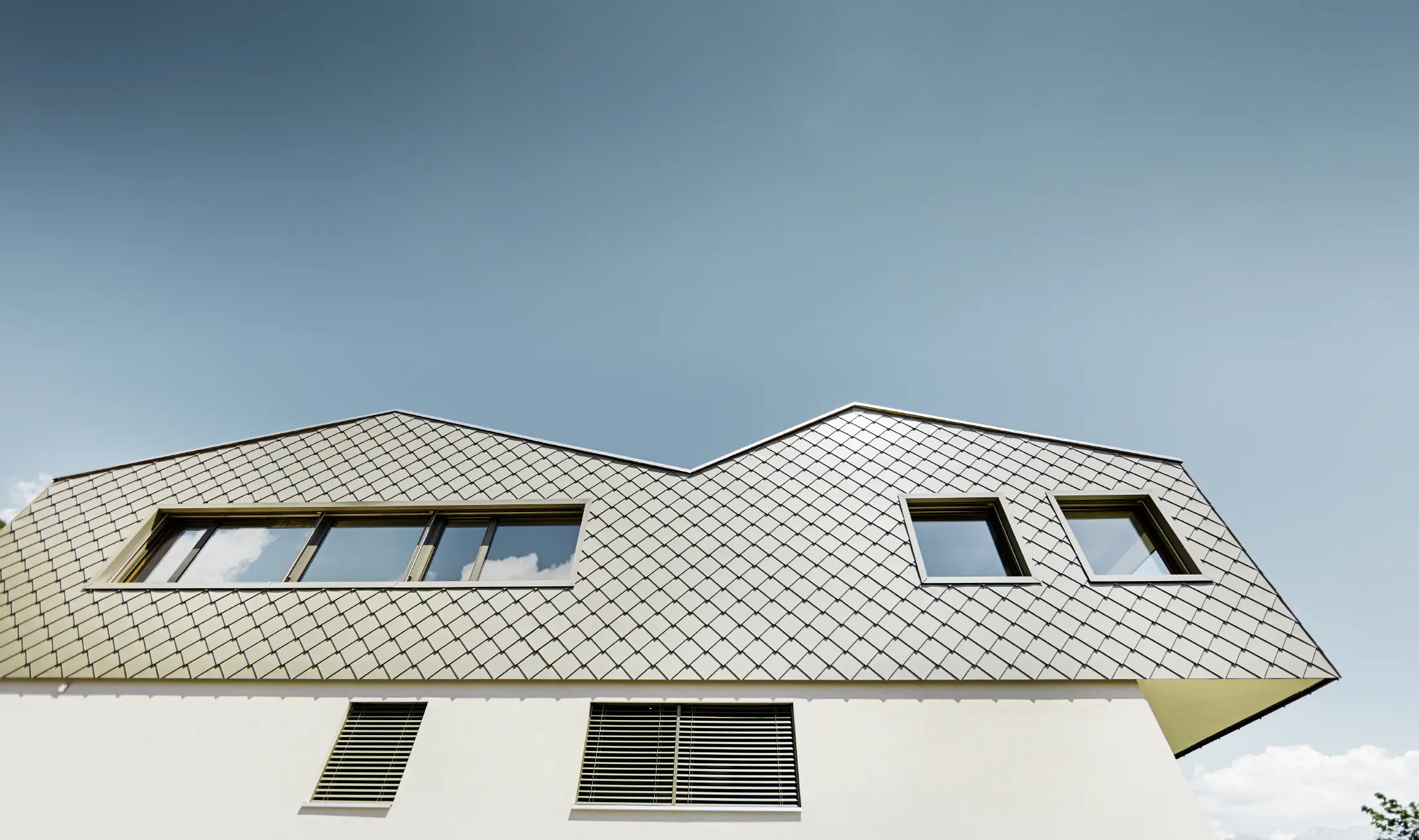 Moderna casa unifamiliare in mezzo ai vigneti della valle del Rodano con 4 diverse superfici del tetto e galleria aperta con facciata a scaglie in bronzo