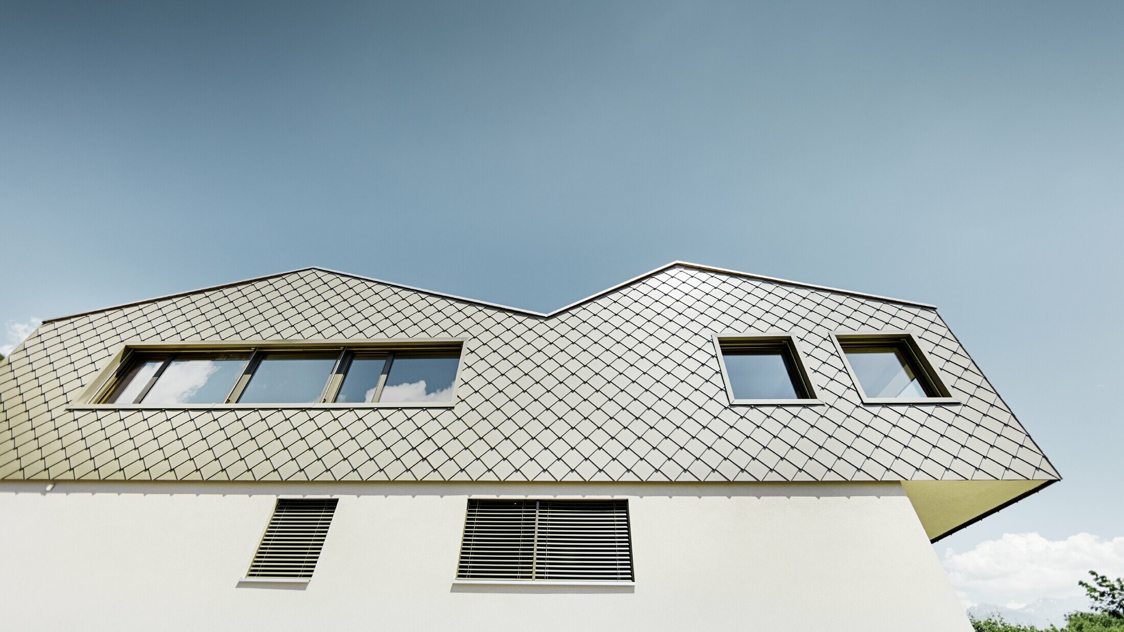Moderna casa unifamiliare in mezzo ai vigneti della valle del Rodano con 4 diverse superfici del tetto e galleria aperta con facciata a scaglie in bronzo