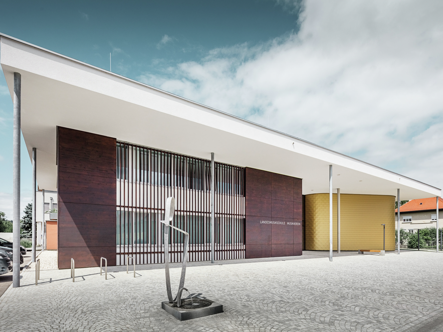 Photo de l'école de musique régionale de Buchkirchen. Le bâtiment est recouvert de 160m² de bardeau de façade PREFA dans la teinte Maya Gold.