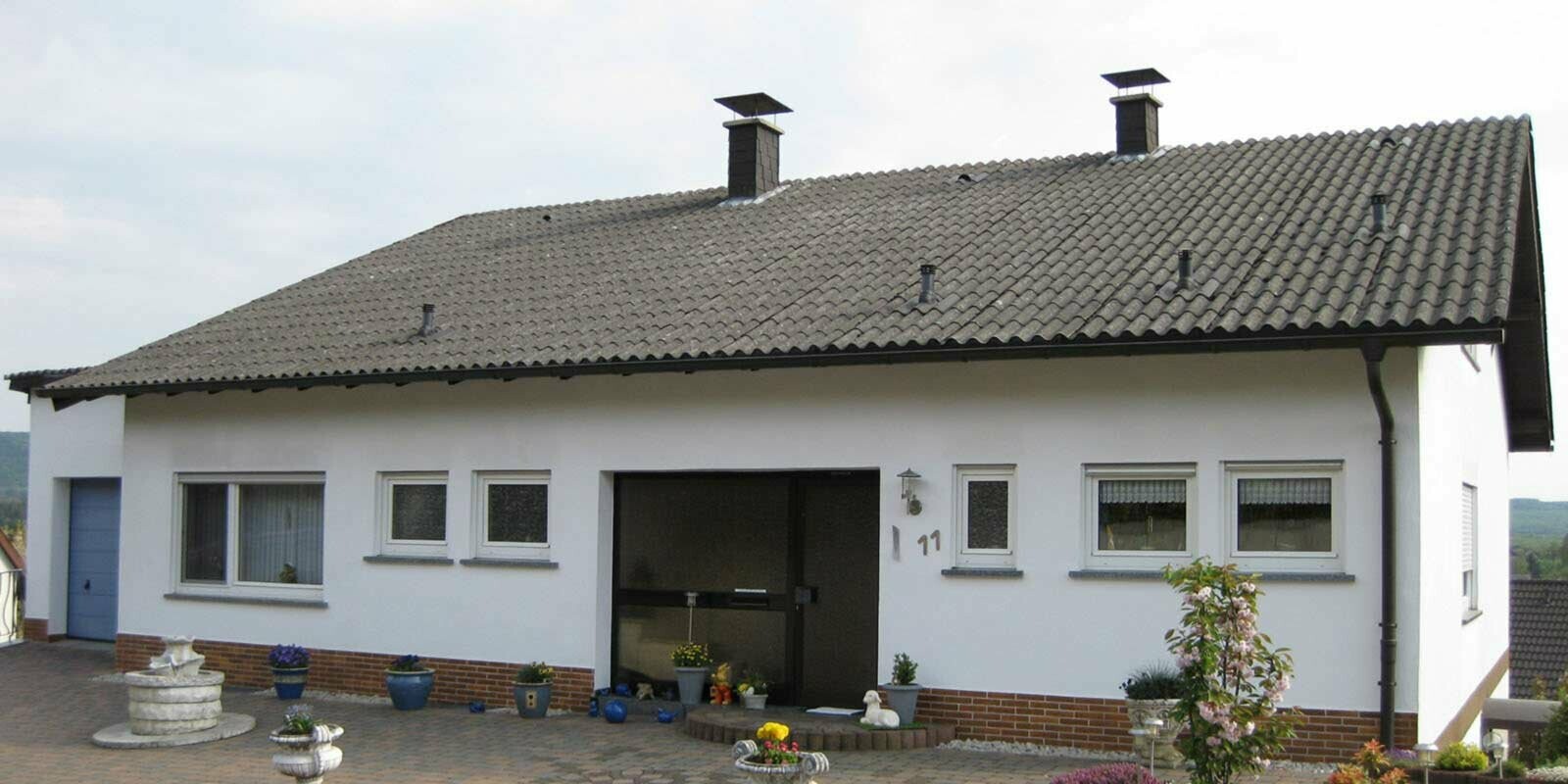 Maison individuelle avec fibrociment ondulé avant la rénovation de toiture à l’aide de tuiles PREFA