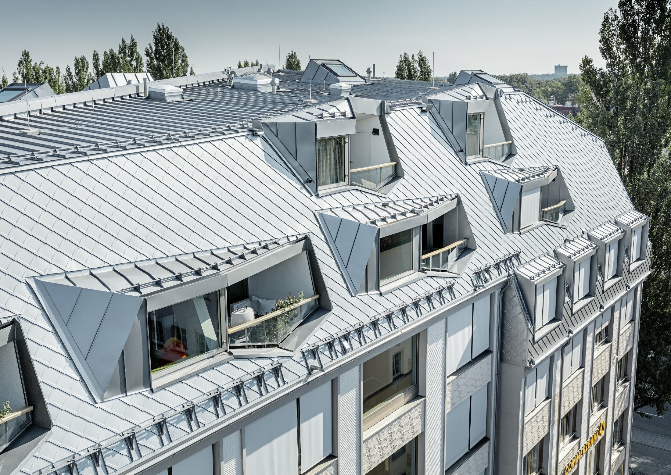 Appartements mansardés rénovés et dotés de spacieuses mezzanines, aménagés dans un immeuble d’habitation et de commerces munichois de la Leopoldstraße, à l’angle de la Hohenzollernstraße — Couverture de toit réalisée avec des losanges de toiture PREFA