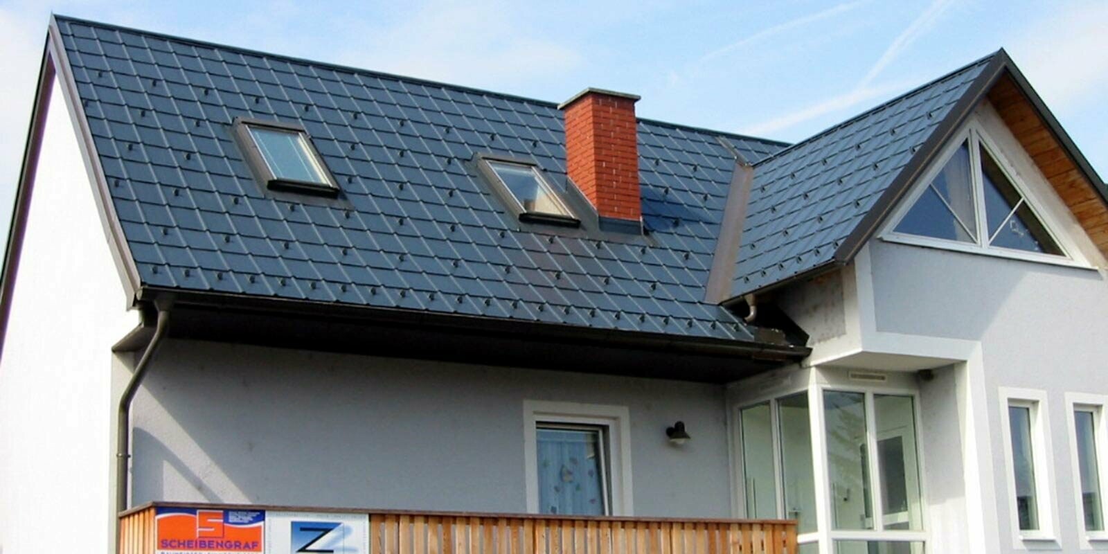 Maison individuelle avec toit à deux pans et façade bleue, toit récemment rénové par PREFA