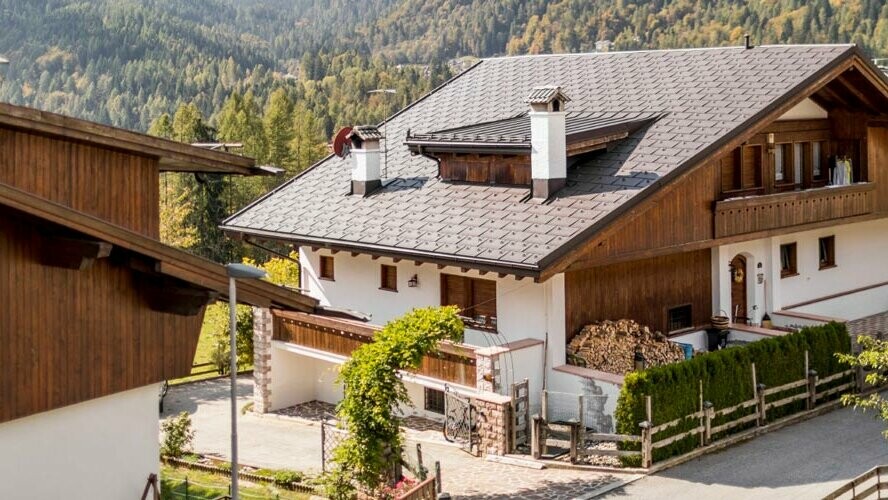 Traditionelles Haus mit nussbrauner PREFA Dacheindeckung und einer Fassade mit Holzelementen und Putz