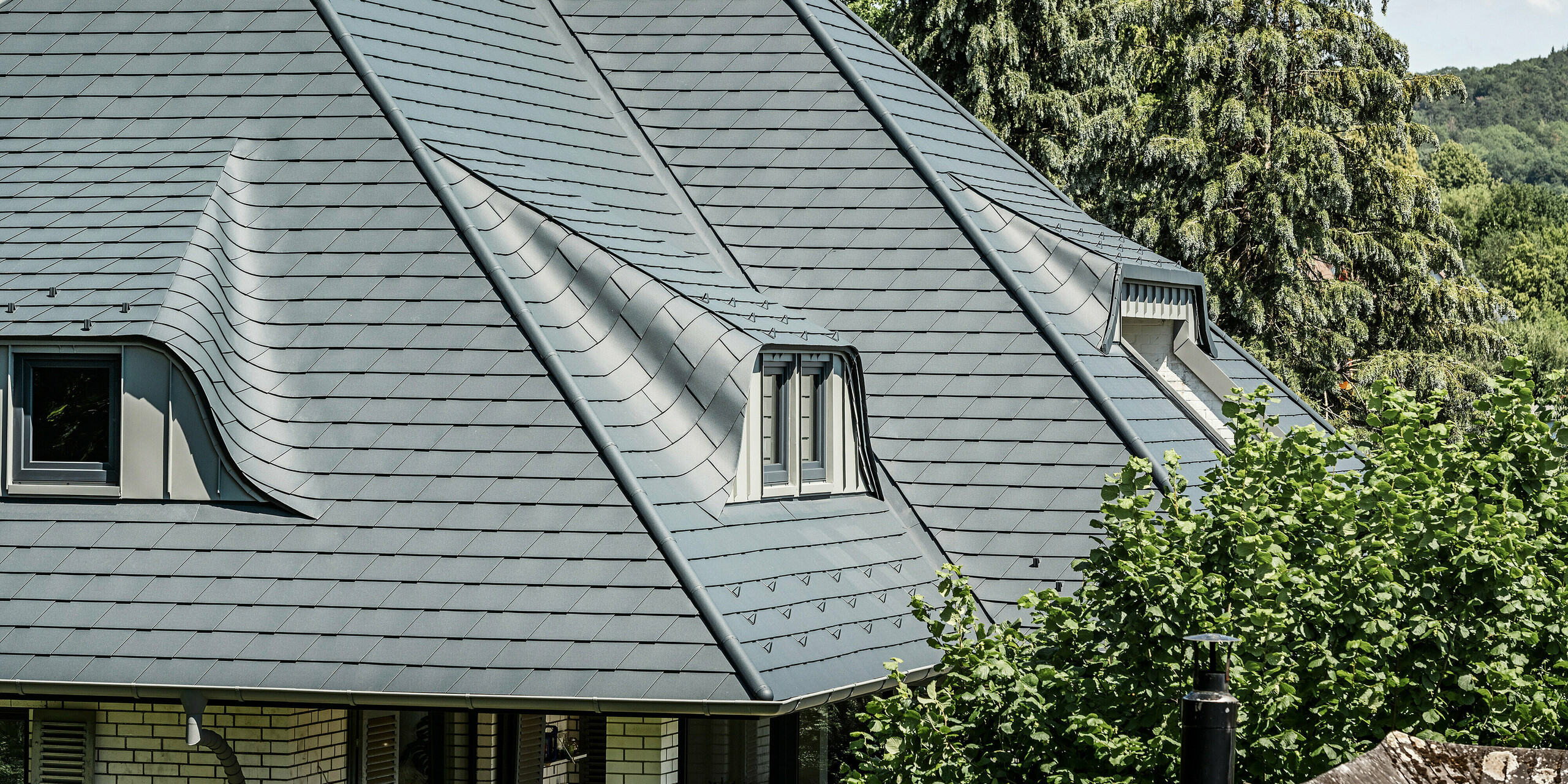 Dachlandschaft mit geschwungenen Gauben auf Einfamilienhaus in Einbeck mit PREFA Dachschindel in P.10 Anthrazit eingedeckt