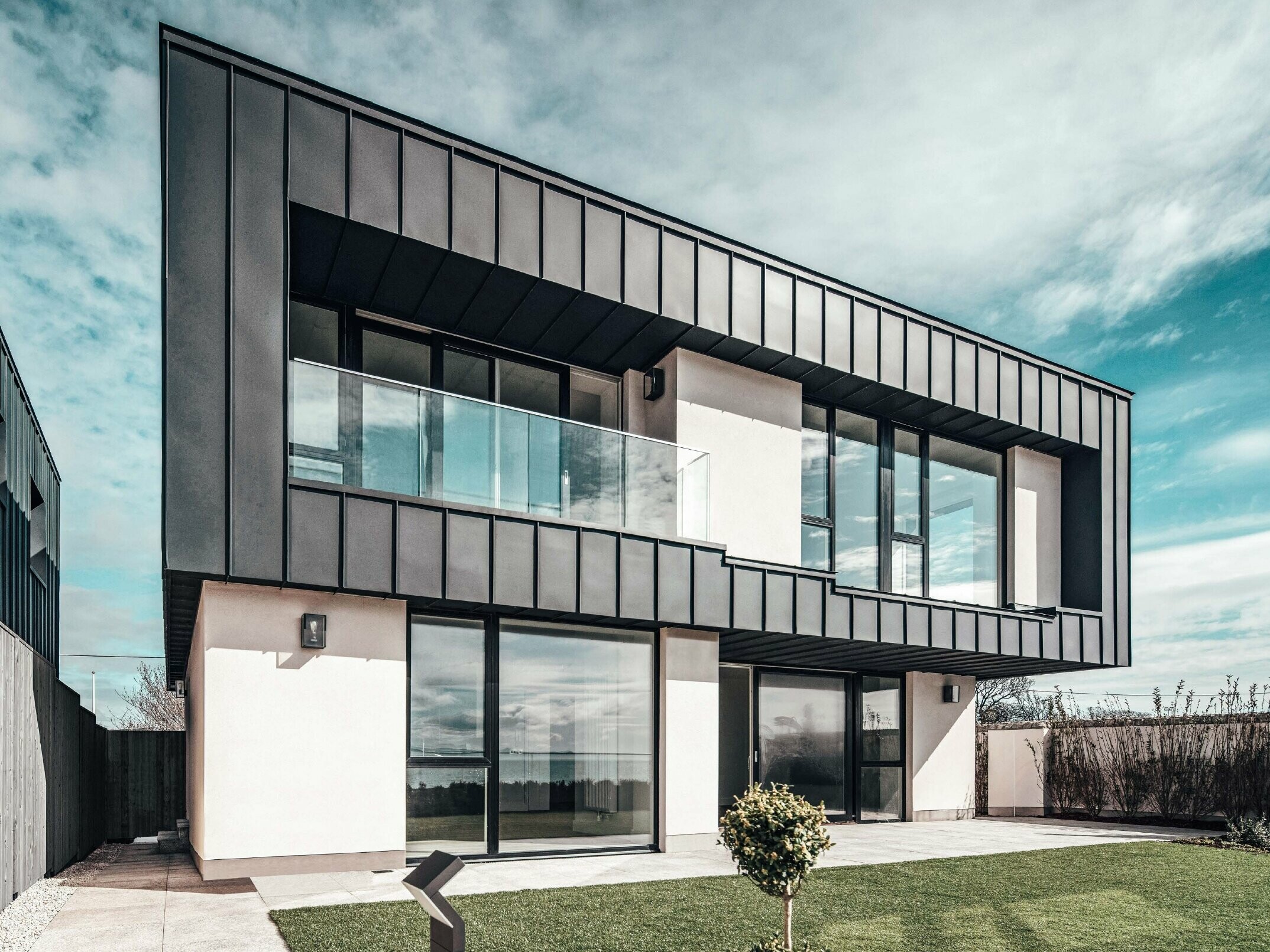 Maison mitoyenne avec toit plat, la façade à l'étage supérieur a été conçue à l'aide d'une façade à joint debout en PREFALZ couleur anthracite.