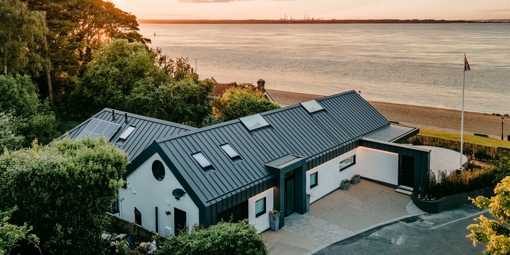 Bungalow auf Isle of Wight, eingedeckt mit PREFA PREFALZ in P.10 Dunkelgrau, aus der Vogelperspektive mit Blick zum Meer.