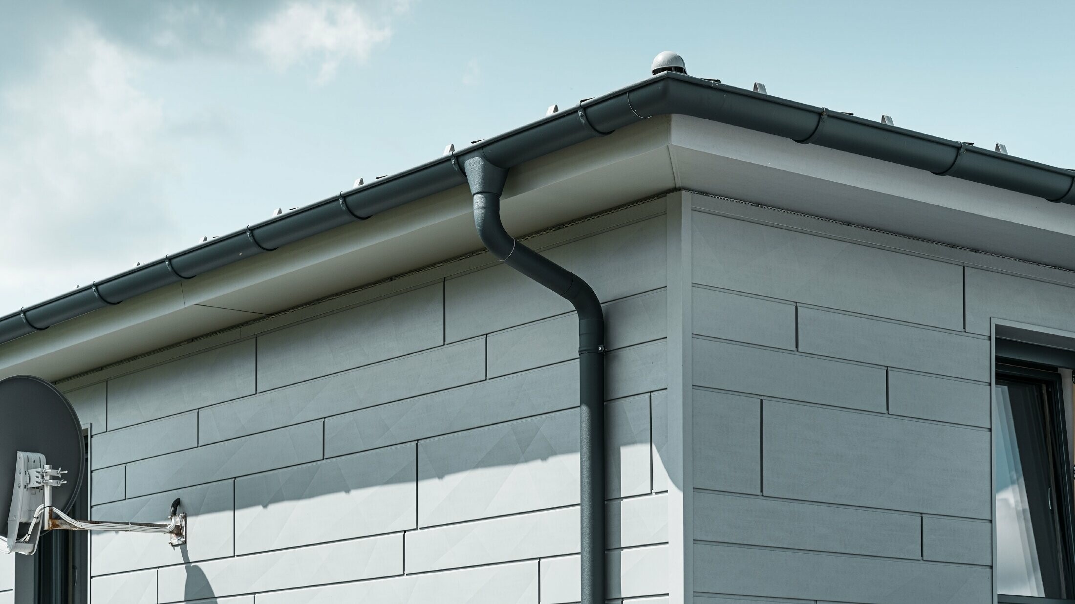 Soffitto con grondaia PREFA, bocchetta e tubo pluviale antracite con facciata in Doga.X PREFA grigio patina