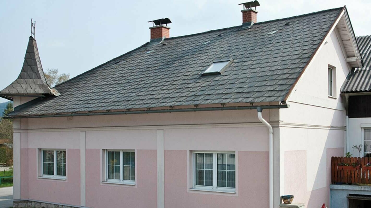 Haus vor der Dachsanierung mit der PREFA Dachplatte in Österreich - zuvor Eternit Faserzement und Türmchen, rosa Fassade