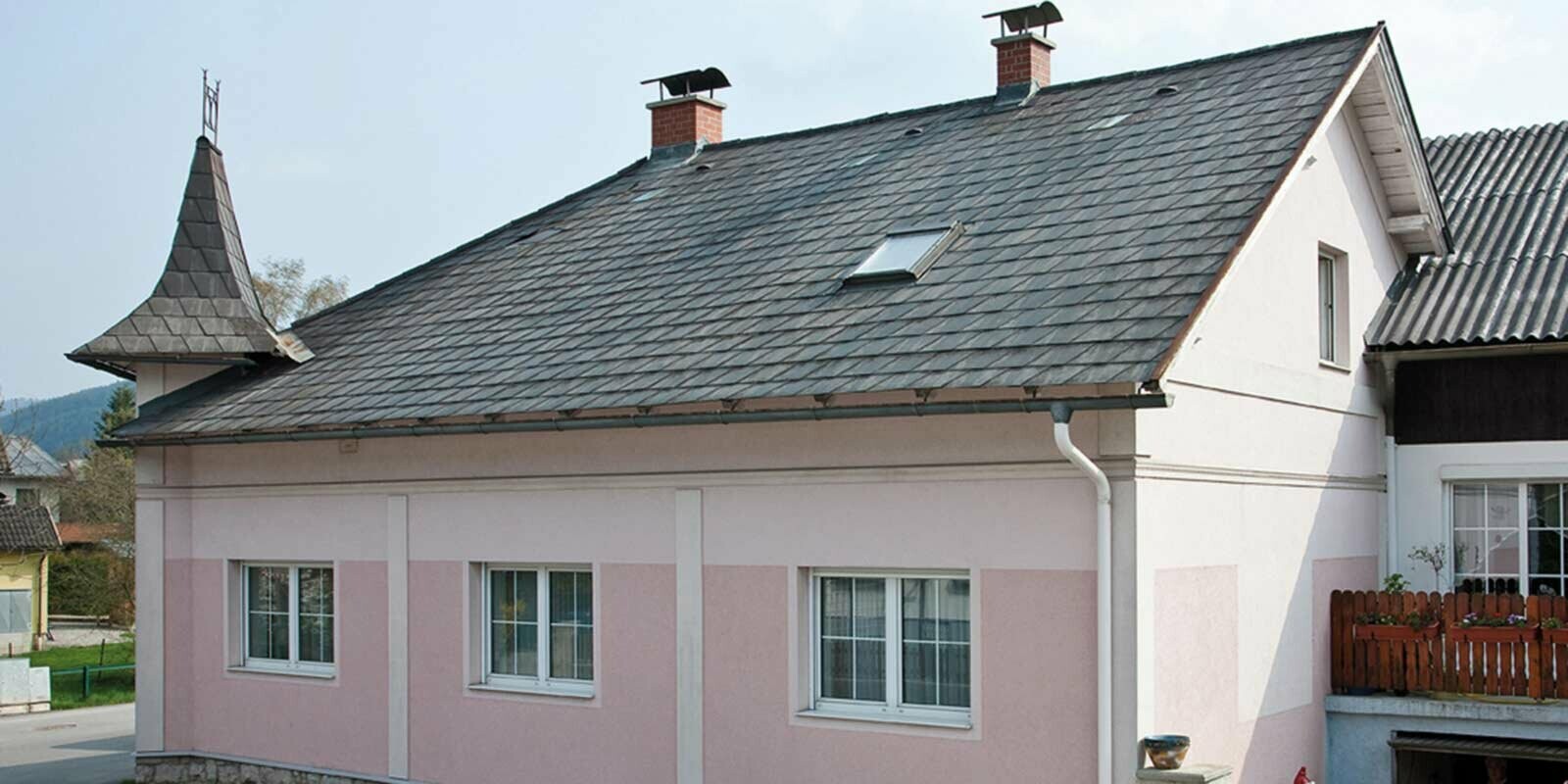 Maison avant la rénovation de toiture à l’aide de tuiles PREFA, en Autriche. Auparavant fibrociment Eternit et tourelle, façade rose