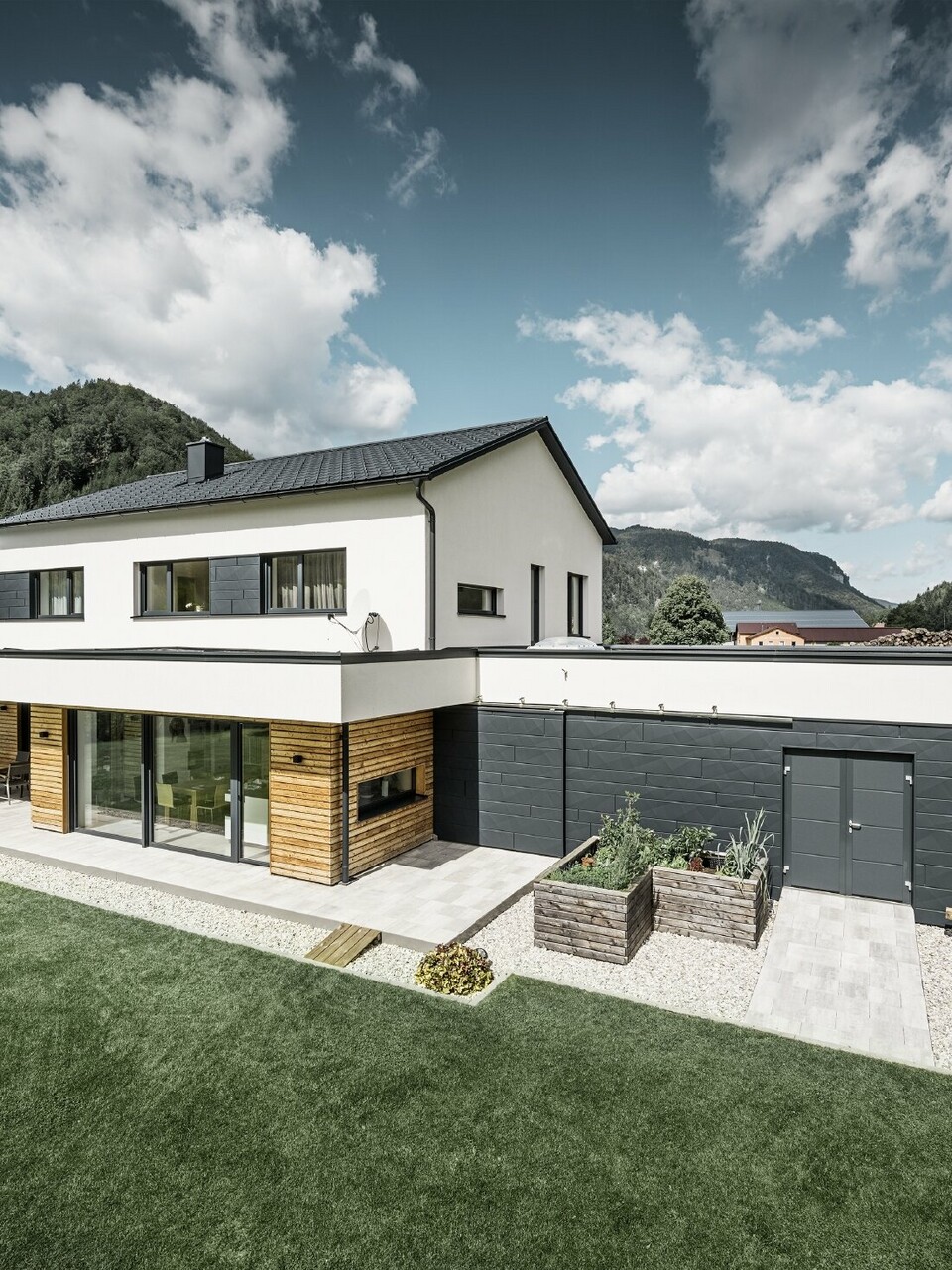 Maison individuelle moderne dans un environnement rural, avec les produits de toiture et de façade PREFA. 