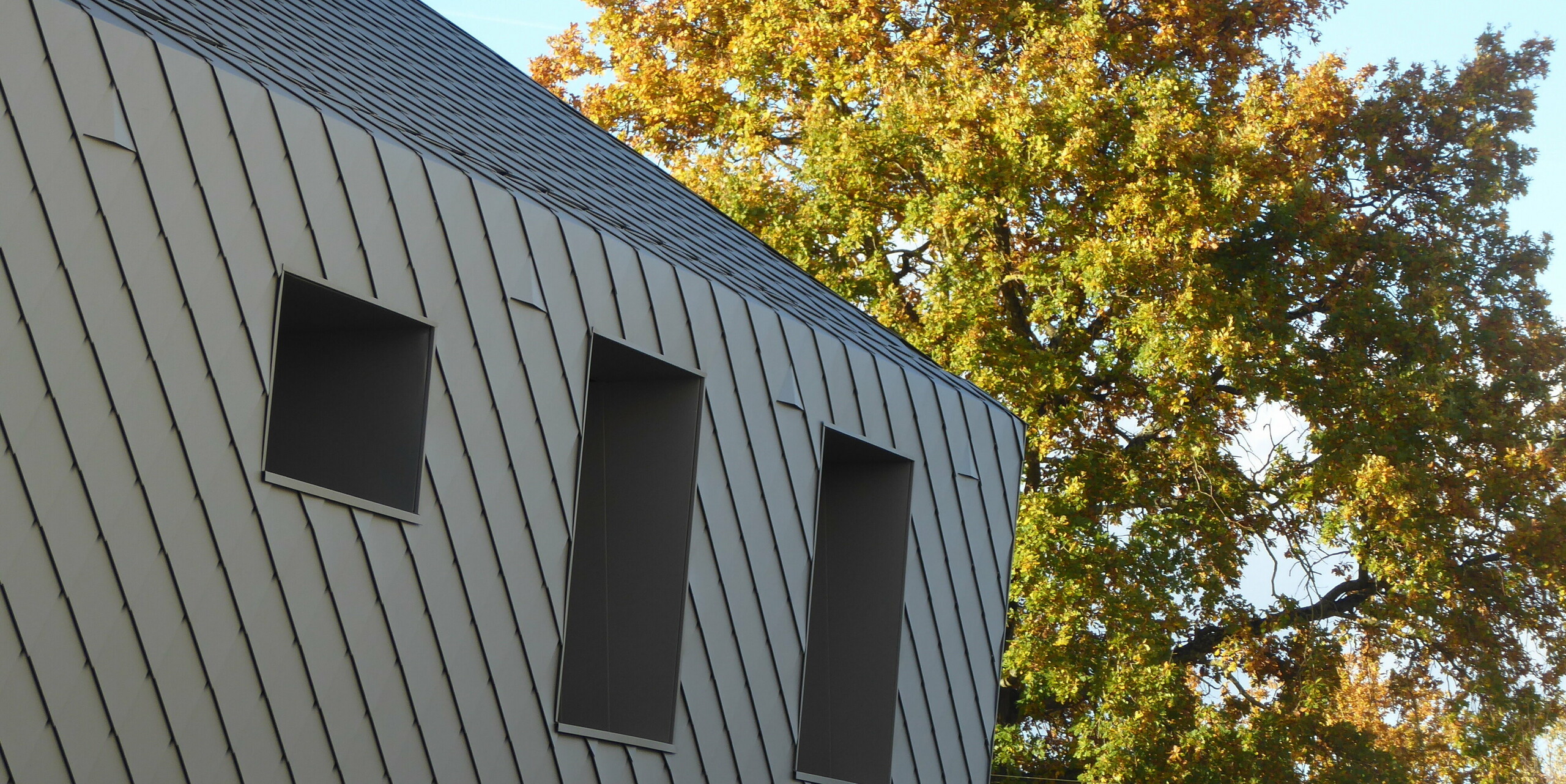Gros plan sur la transition de la toiture à la façade avec des losanges PREFA en aluminium sur une maison individuelle à Acigne
