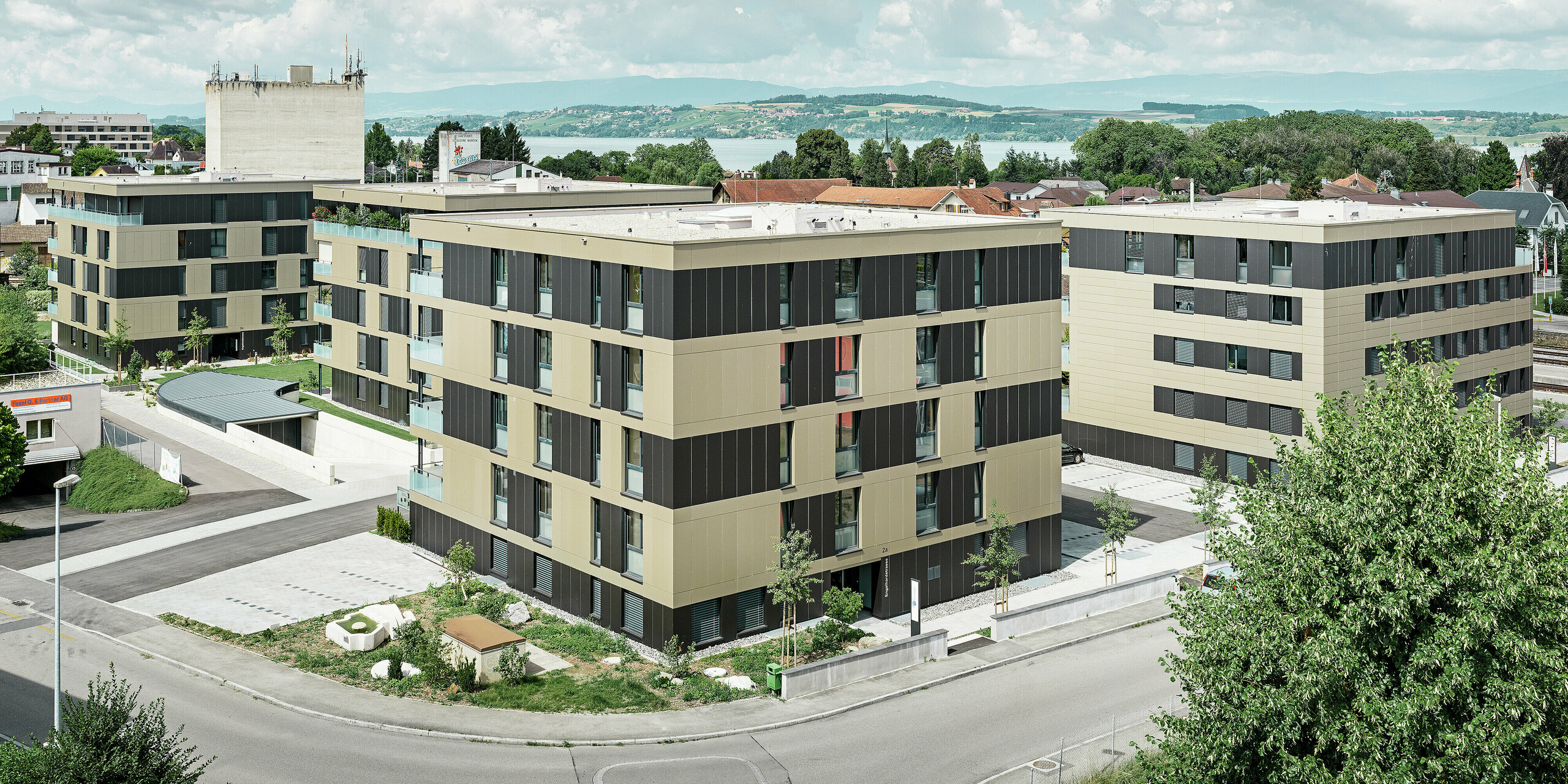 Die markante Architektur der Wohnanlage in Murten (CH) wird durch den Einsatz von PREFABOND Aluminium Verbundplatten in den Farben Bronze und Schwarzgrau perfekt umhüllt. Die langlebige und pflegeleichte Blechfassade schützt das Gebäude vor äußeren Witterungseinflüssen und sorgt gleichzeitig für eine moderne und elegante Ästhetik, die das gesamte Umfeld bereichert.