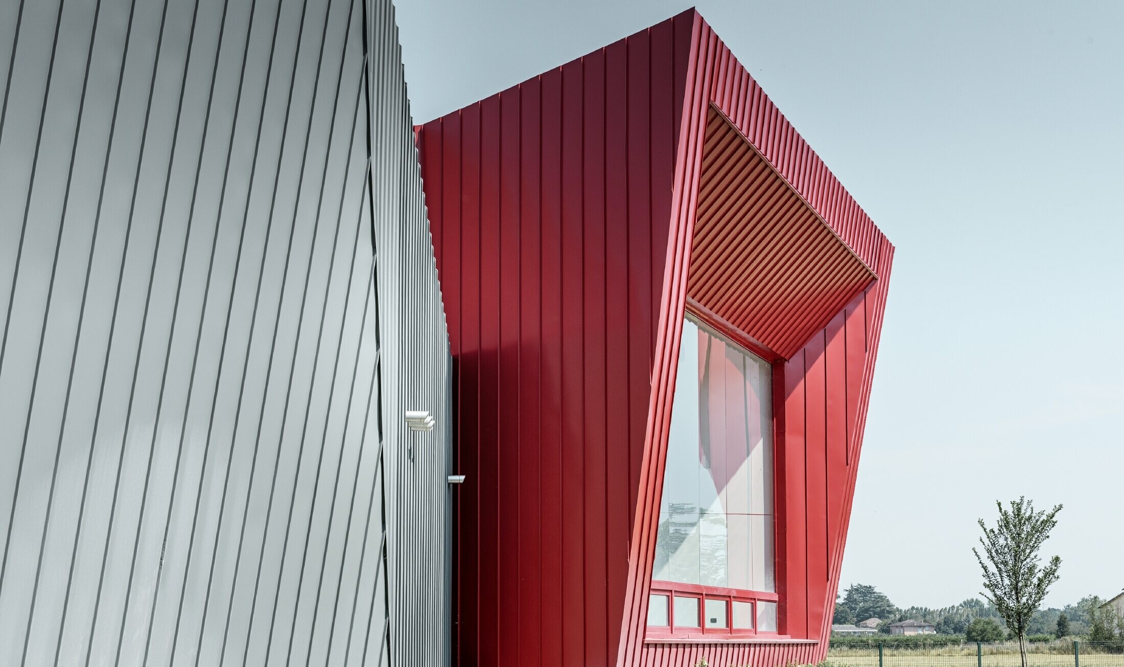 Moderno centro sportivo di Dieci a Montecchio Emilia, Italia, con tribuna con facciata in alluminio con Prefalz in grigio chiaro e Falzonal in rosso carmine 