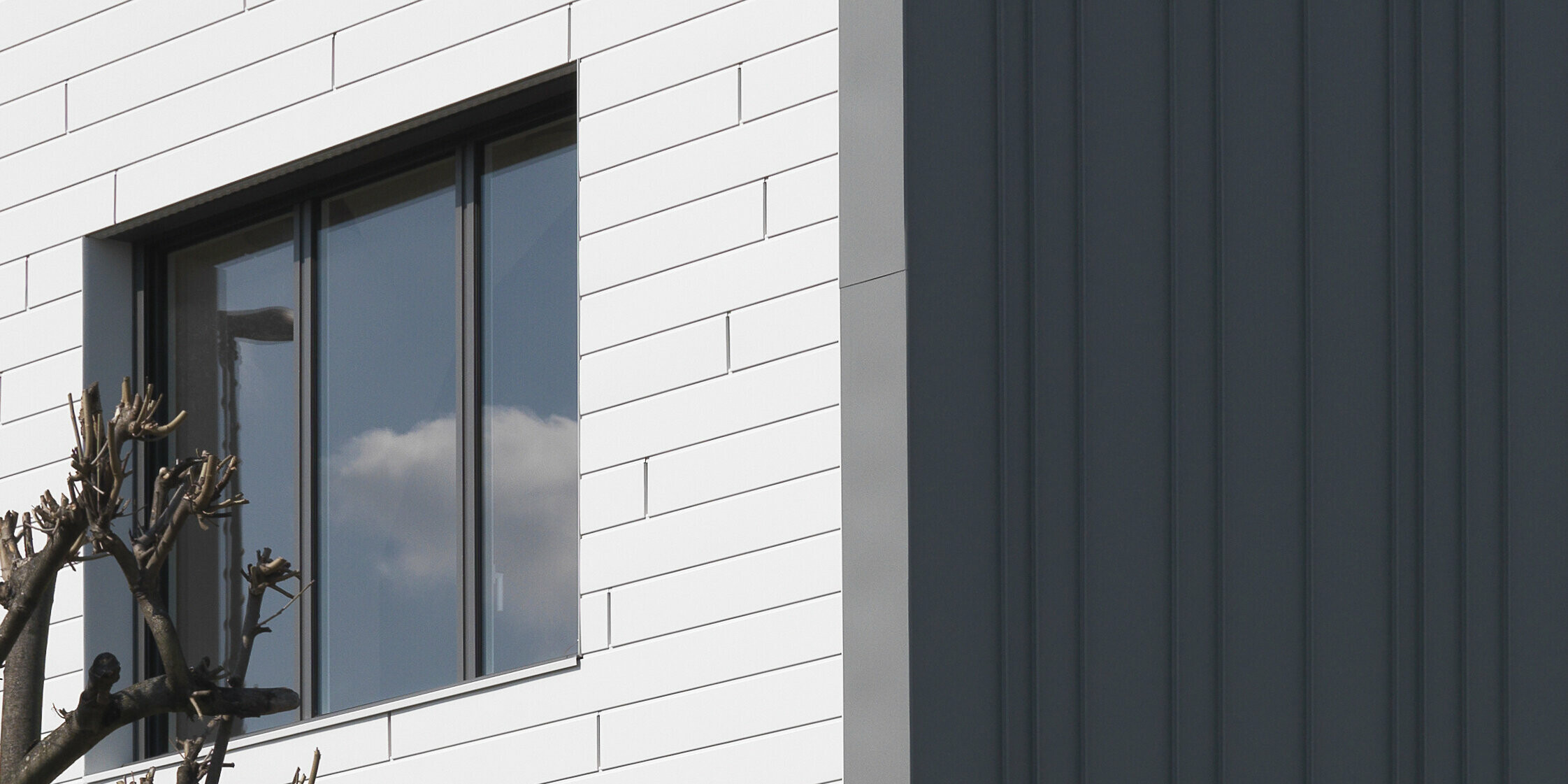 Vue détaillée d'une maison familiale à Houilles (France). Pour le bâtiment, les Siding PREFA en P.10 blanc pur ont été combinés en façade et PREFALZ en P.10 gris souris en toiture et façade.
