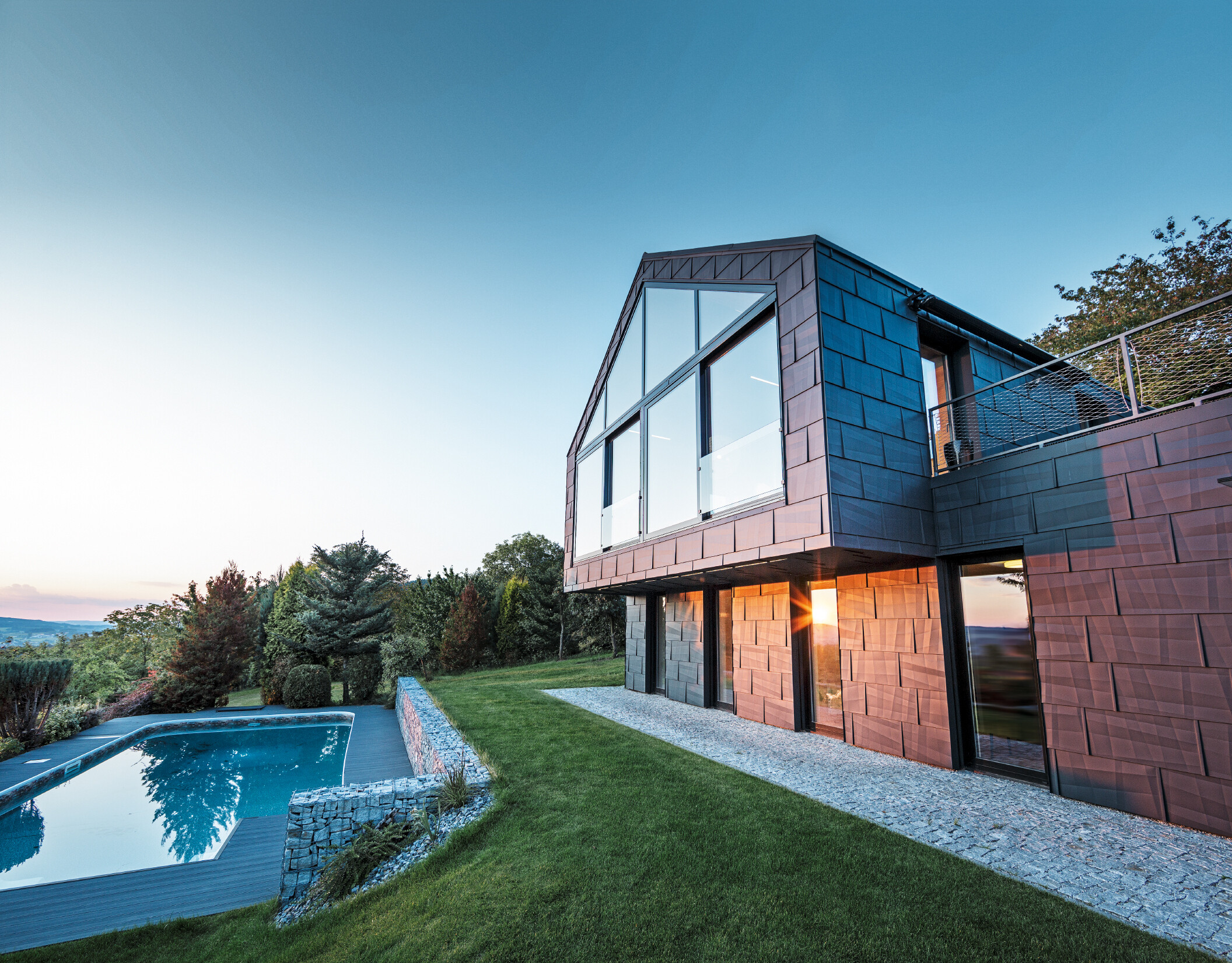 Façade en aluminium d’une maison individuelle avec panneaux de façade FX.12 PREFA couleur P.10 anthracite au coucher du soleil. 