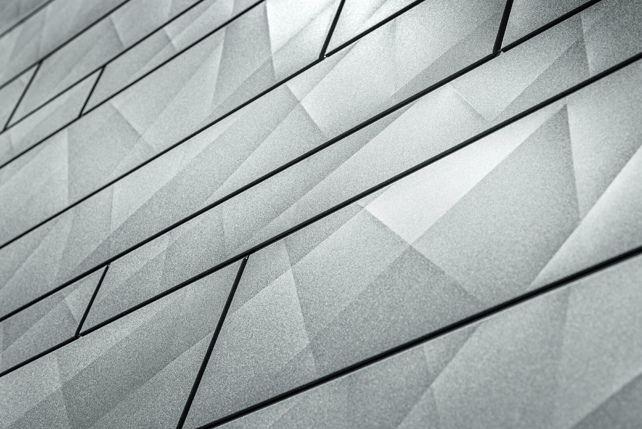 Zoom del pannello per facciata doga.X in grigio pietra di PREFA. In corrispondenza dei pannelli si distinguono i bordi irregolari con l’effetto naturale della pietra.