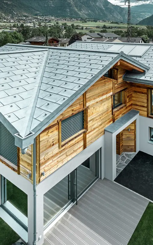 Chalet suisse avec une toiture en alu de PREFA. Le choix s’est porté sur la tuile R.16 couleur gris pierre. À l’étage supérieur, le choix s’est porté sur une façade en bois rustique.