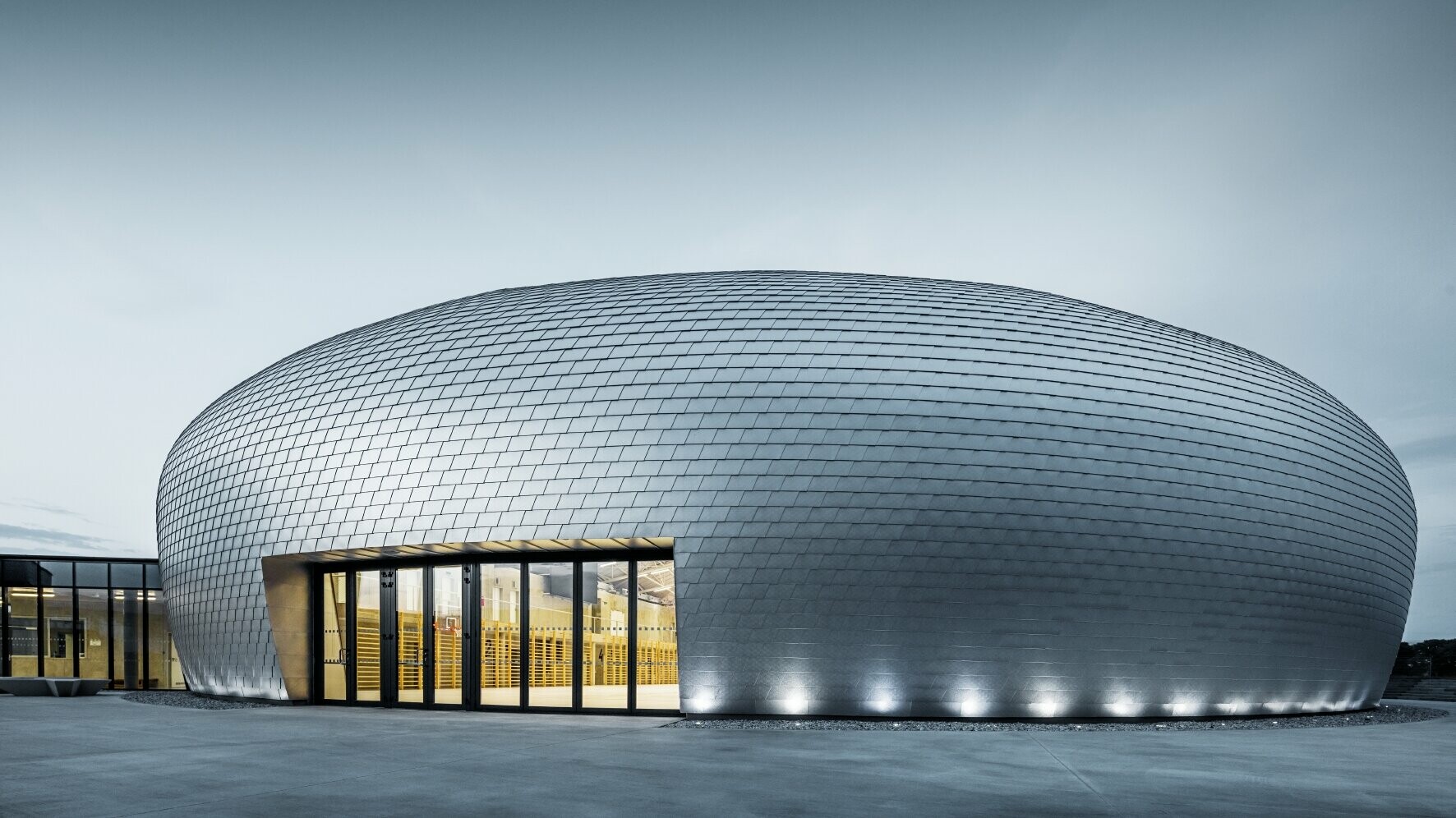 Die Sporthalle in Tschechien erinnert in ihrer Form an ein UFO - dazu wurden 20.000 PREFA Wandschindeln in Naturblank verlegt
