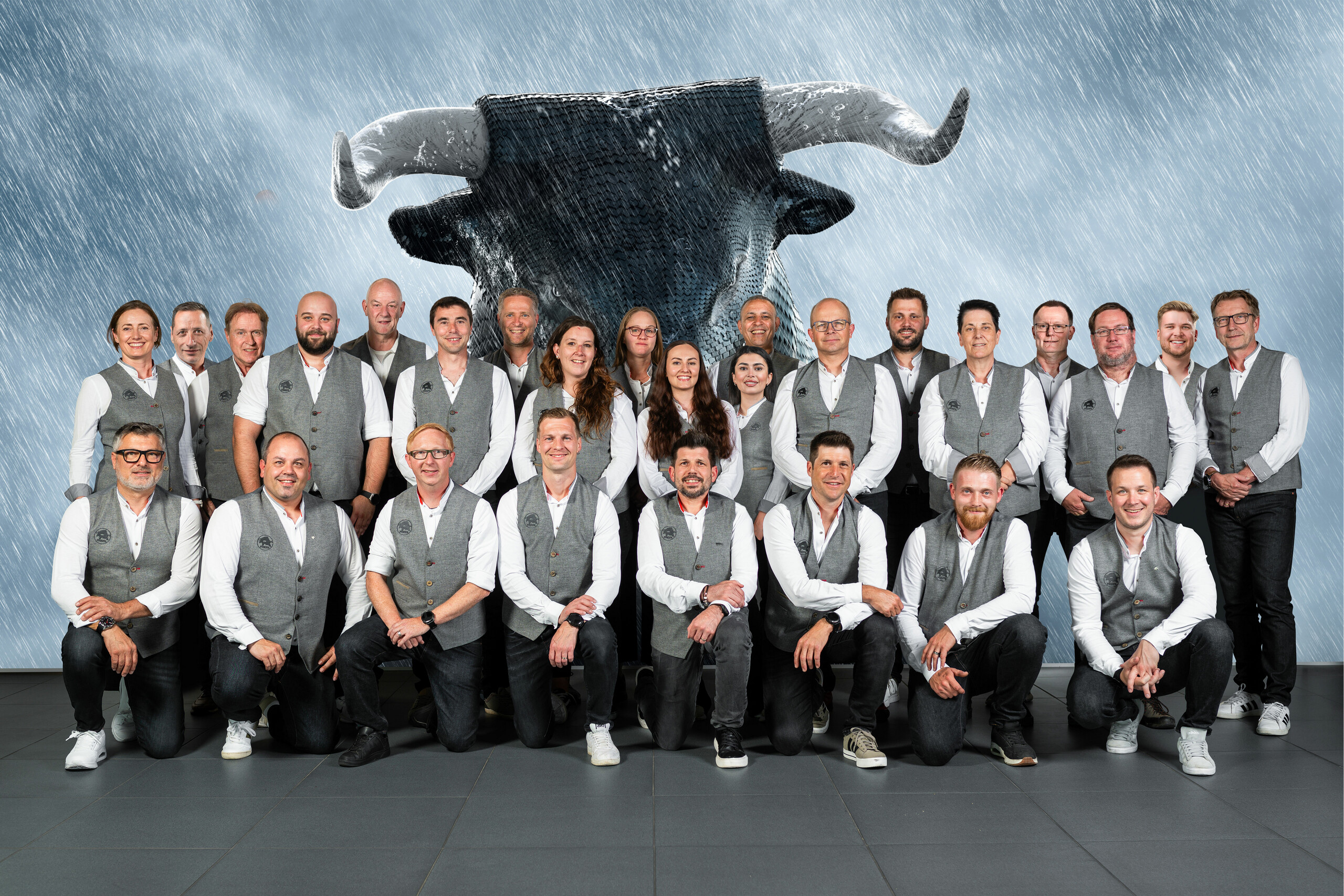 PREFA Mitarbeiter aus der Schweiz vor einer Leinwand, auf welcher der PREFA Stier zu sehen ist.