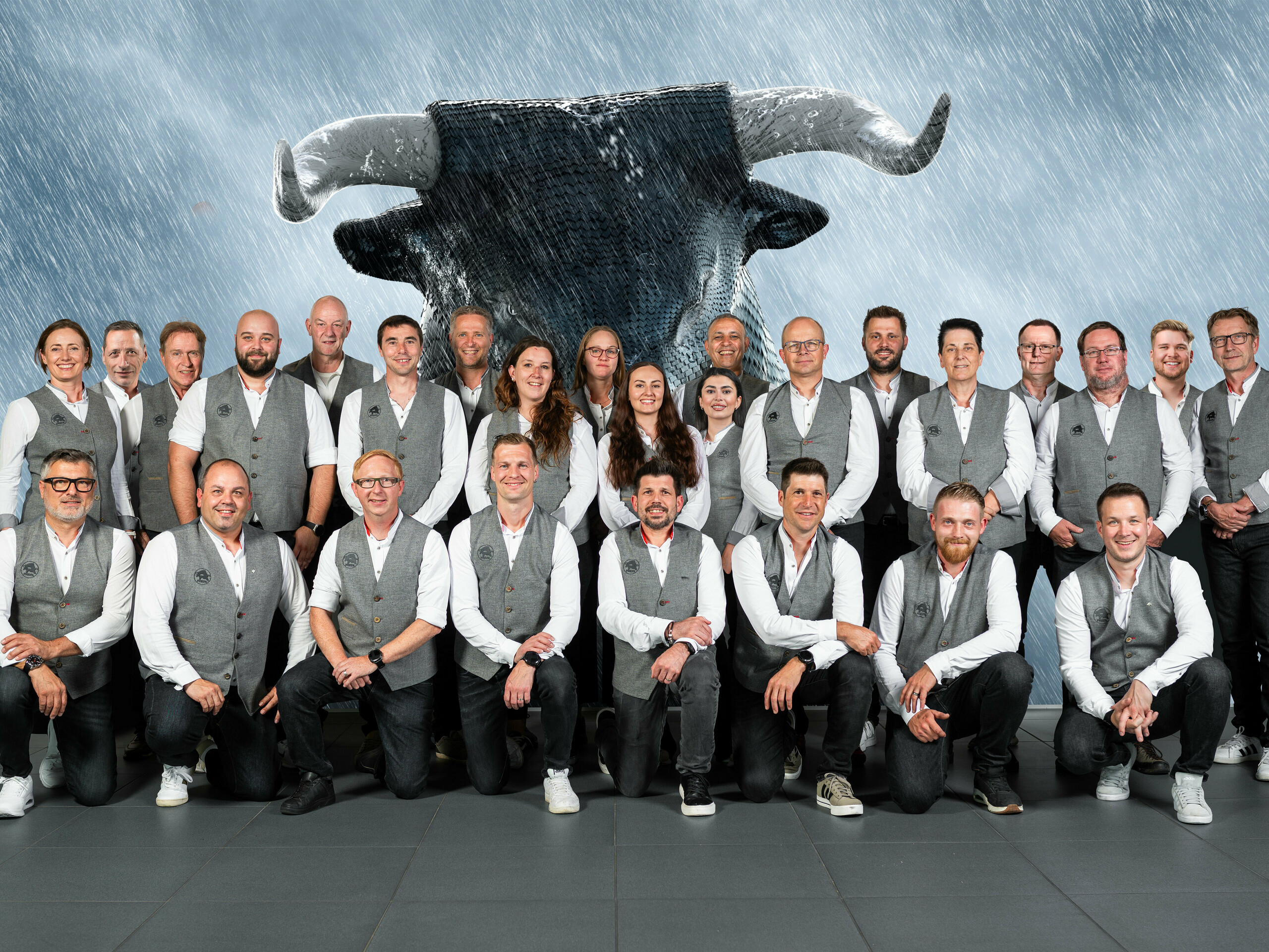 PREFA Mitarbeiter aus der Schweiz vor einer Leinwand, auf welcher der PREFA Stier zu sehen ist.