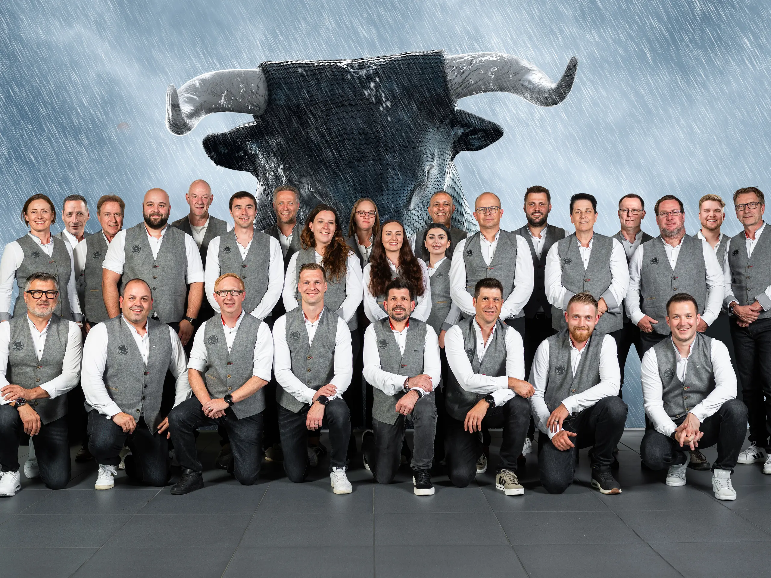 PREFA Mitarbeiter aus der Schweiz vor einer Leinwand, auf welcher der PREFA Stier zu sehen ist.
