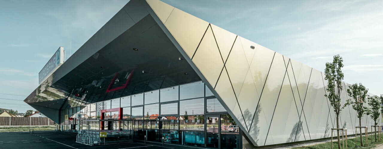 Filiale Spar à Wels avec une façade moderne en aluminium, recouverte de panneaux composites PREFA couleur vermeil.
