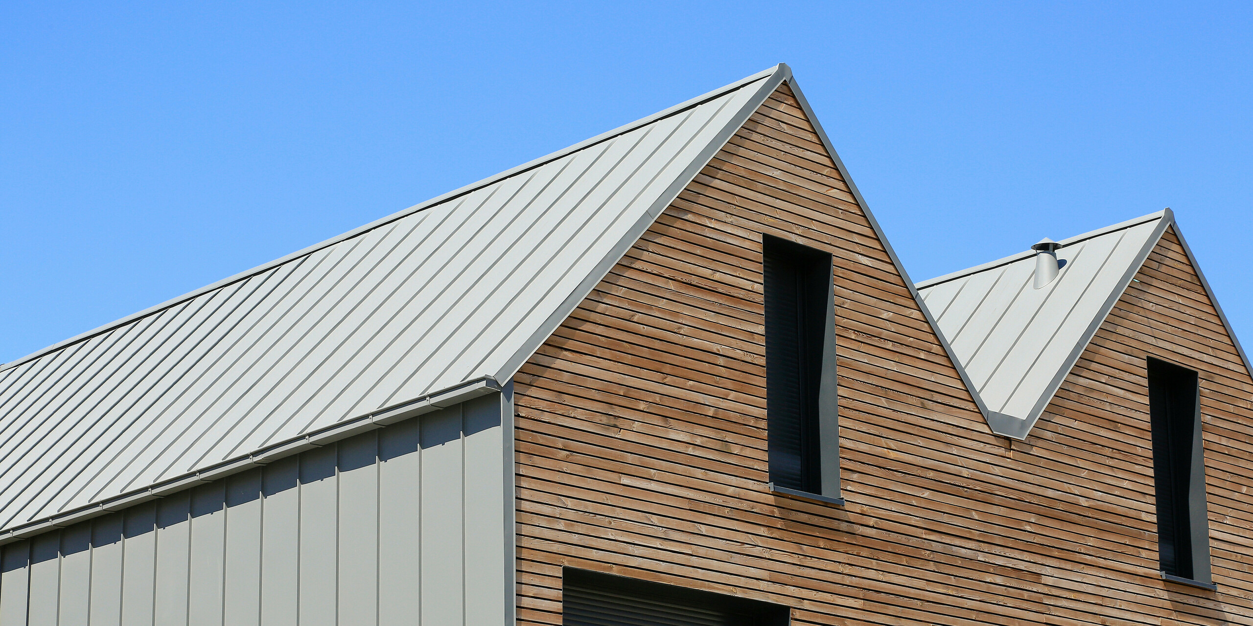 Le joint debout PREFALZ en gris souris s'étend sur les façades et les toits à pignon d'un lotissement mitoyen à Mundolsheim. Les coques uniformes du bâtiment en aluminium créent une image globale harmonieuse.