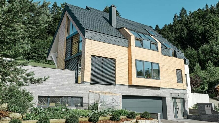 Edificio di nuova costruzione con facciata in legno chiaro e tetto con scaglie a rombo PREFA in P.10 antracite