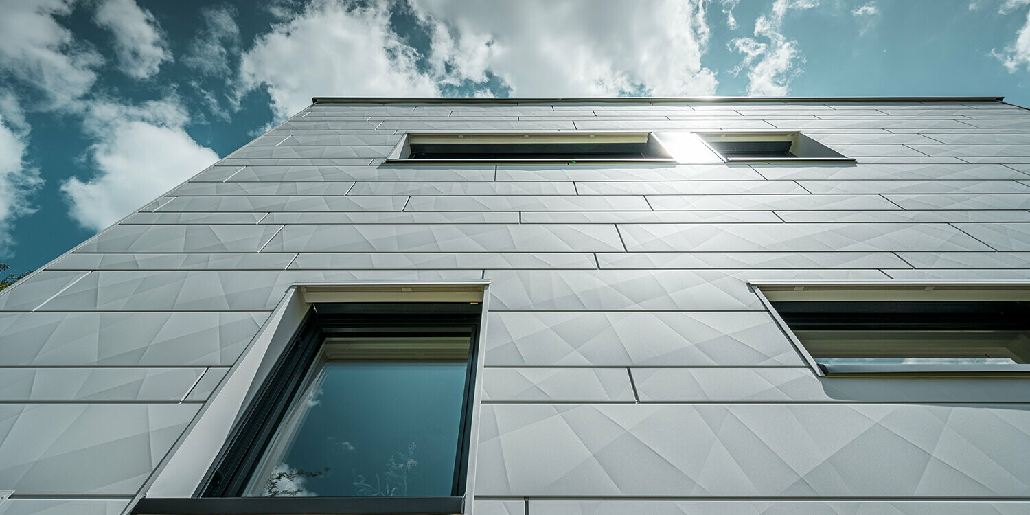 Photo de la façade en Siding.X couleur P.10 blanc Prefa, prise depuis le bas.