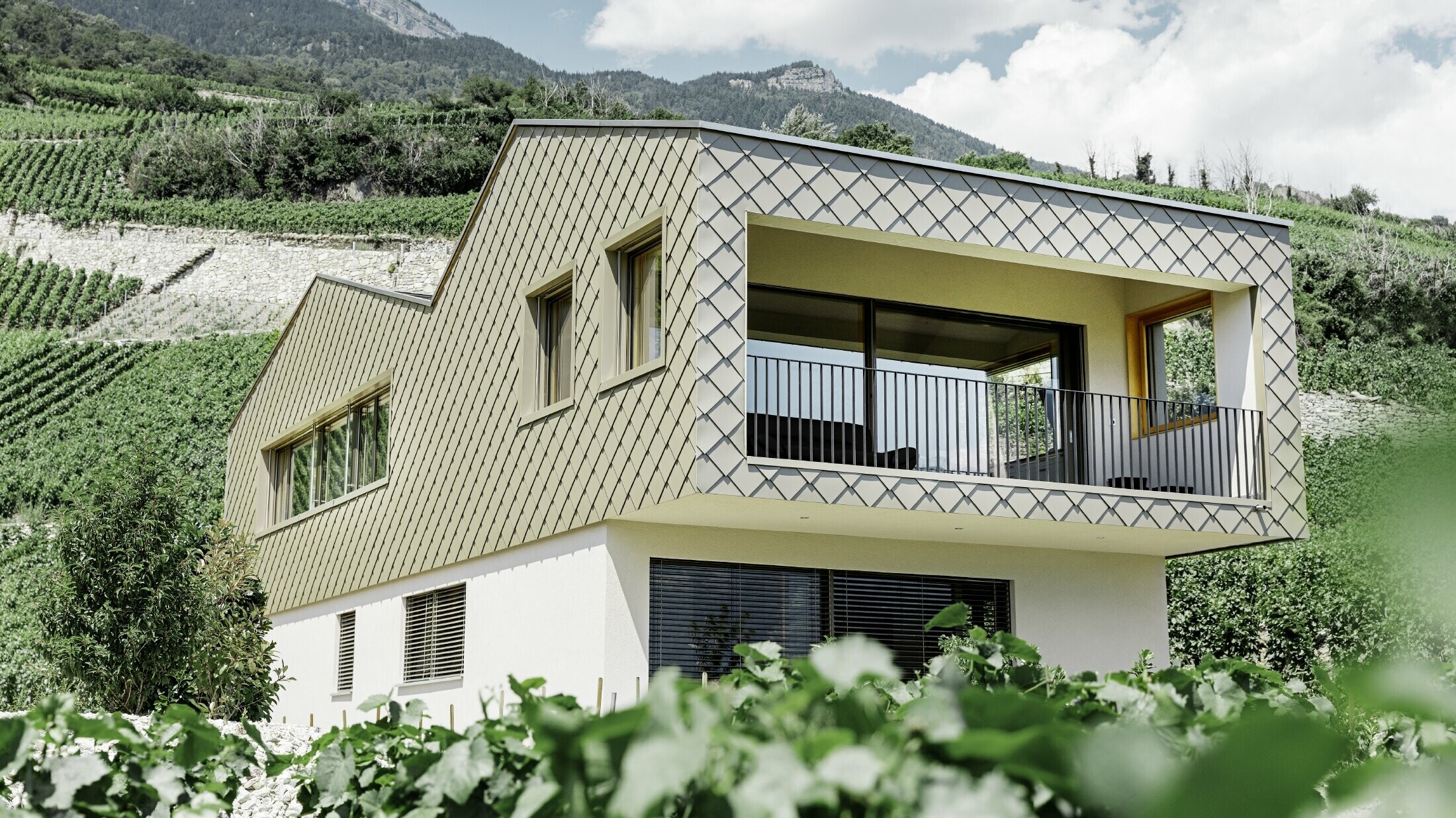 Maison individuelle moderne au cœur des vignobles de la vallée du Rhône avec quatre pentes de toit et grand balcon couvert — Façade habillée de losanges PREFA de couleur bronze