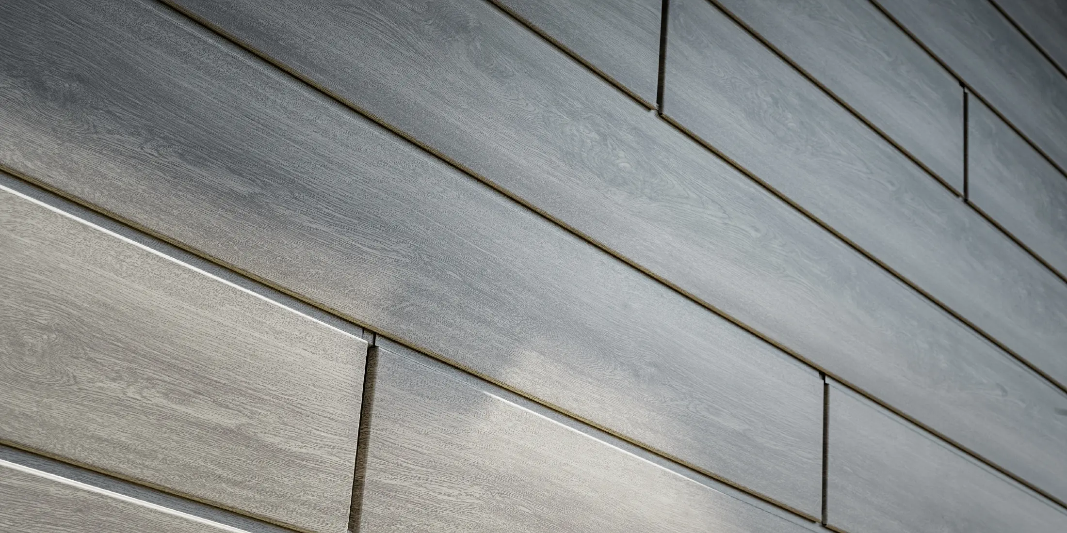Gros plan sur la façade en aluminium PREFA Sidings. Les panneaux en aluminium ont été posés horizontalement et présentent un aspect bois - chêne gris.