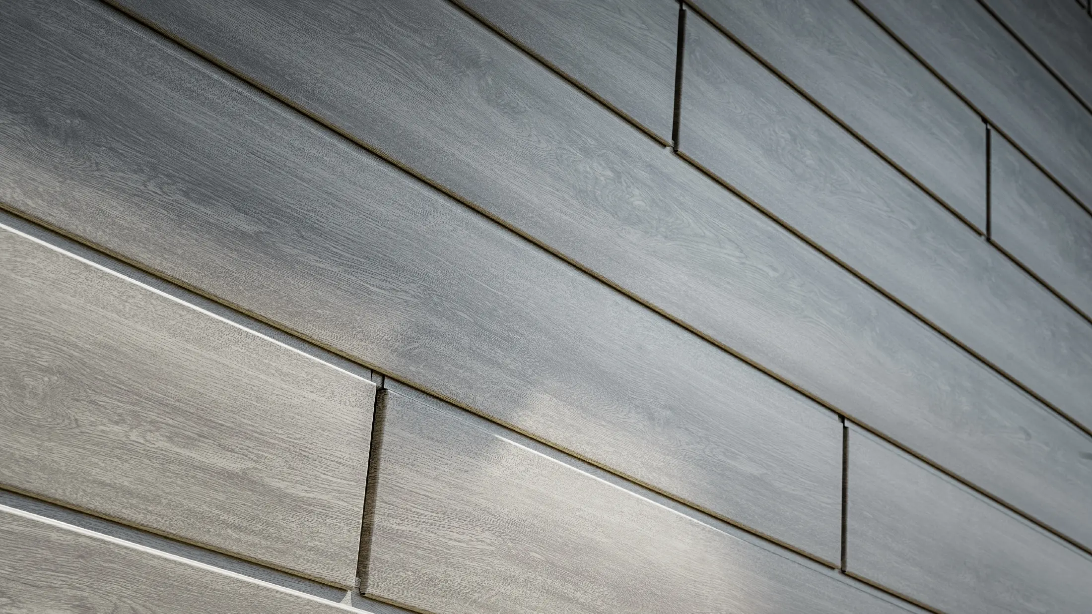 Primo piano della facciata in alluminio PREFA Sidings, i pannelli in alluminio sono stati posati orizzontalmente e hanno un effetto legno - rovere grigio.