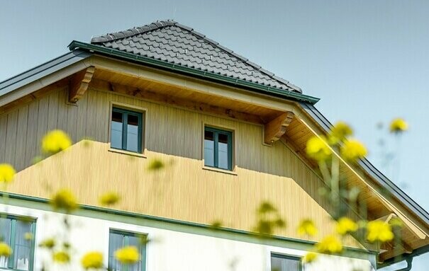 Rivestimento del timpano con pannelli in alluminio di PREFA con effetto legno (rovere naturale), le doghe di rivestimento sono state posate in verticale ed includono il rivestimento dell'intradosso del tetto
